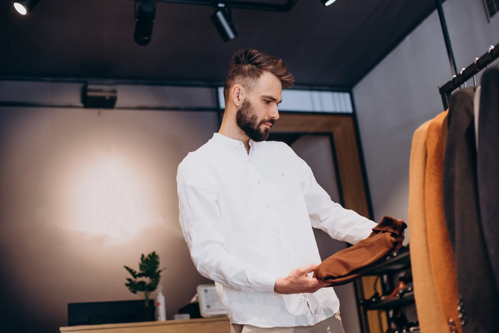 A shop owner selecting clothing in a softly lit retail store