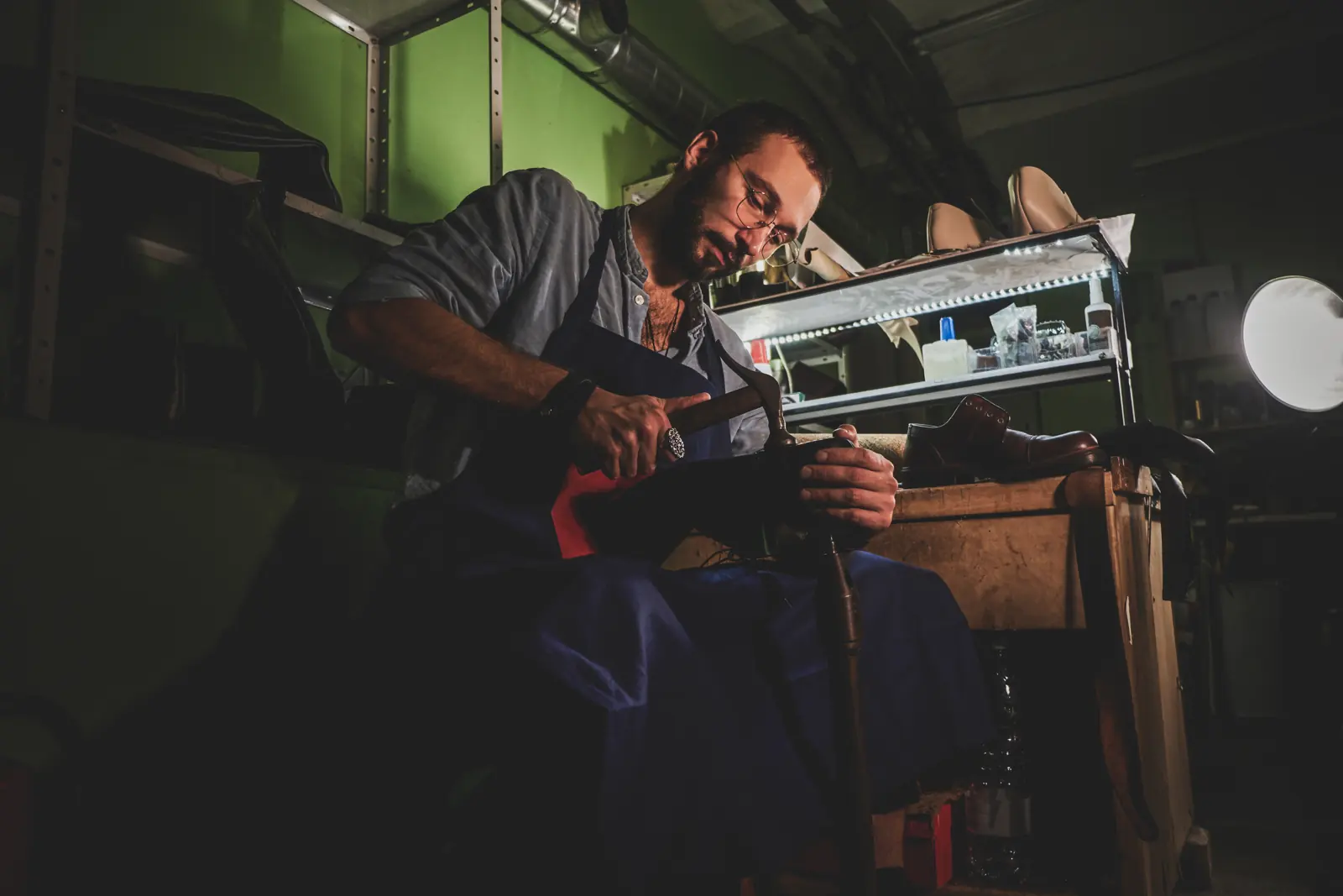 A repair specialist working by lamplight in a small workshop