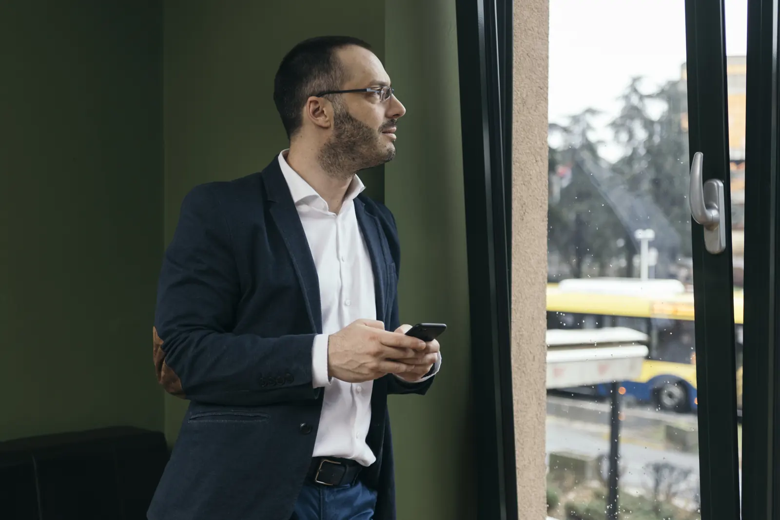 A professional standing beside a window in directional natural light